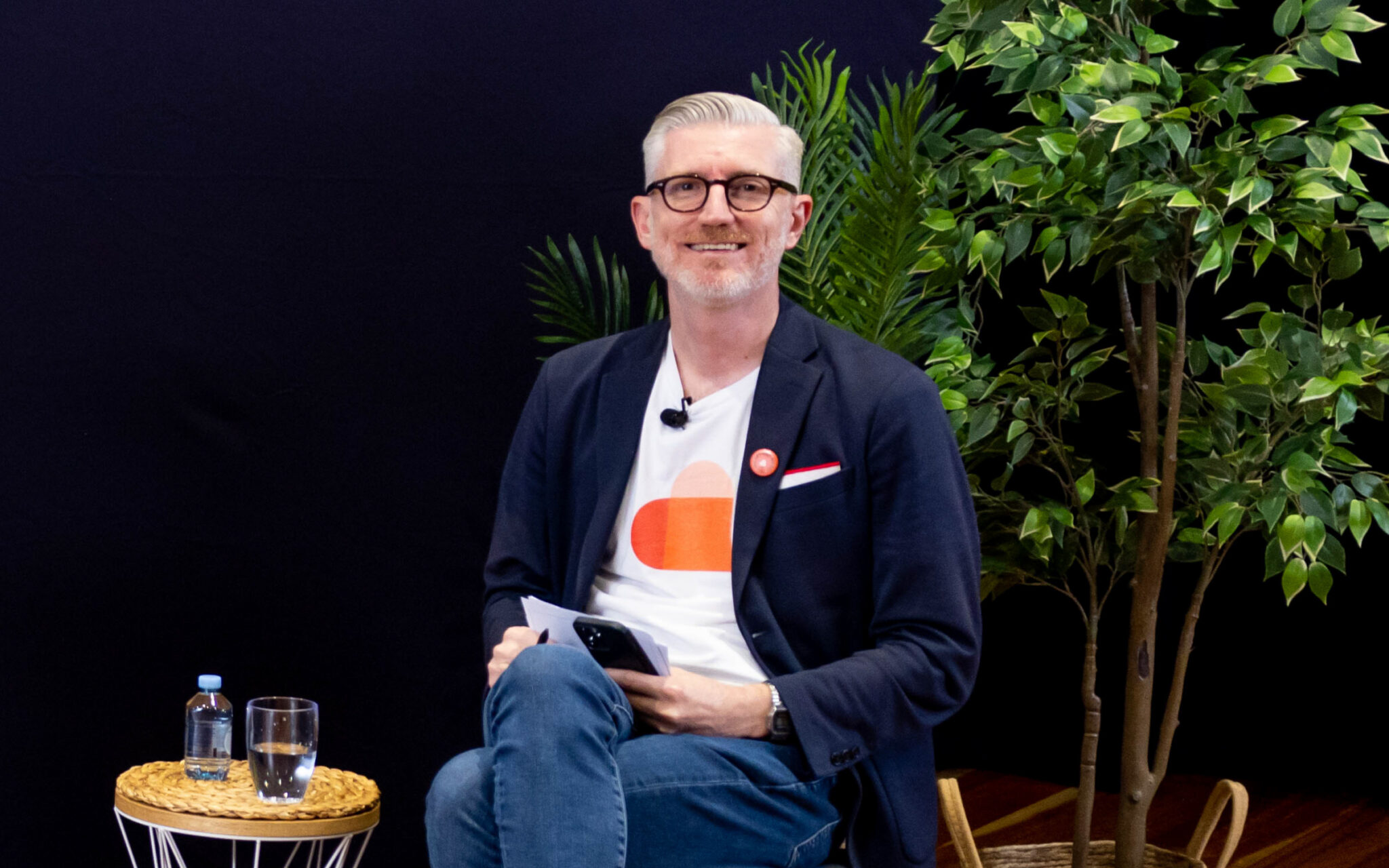 Image of a man sitting on a chair with his legs crossed.