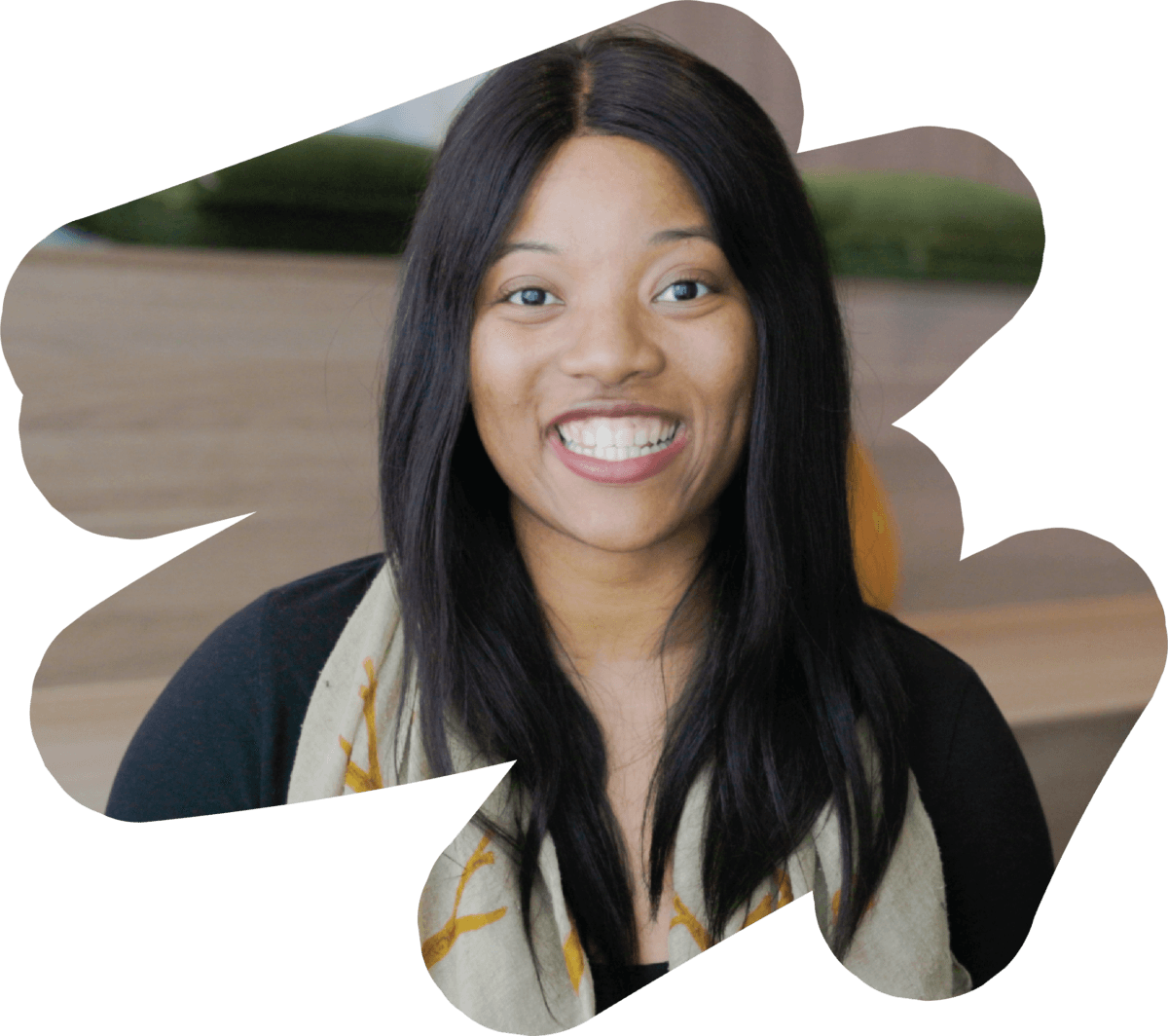 Plan Manager sitting and smiling at the camera. She has long black hair and is wearing a colourful scarf.
