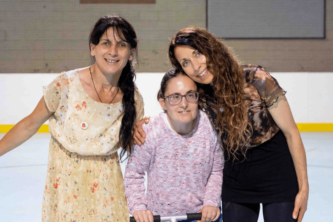 Angela, Tiffany and Sophia are al standing in a skating rink, smiling and looking at the camera.